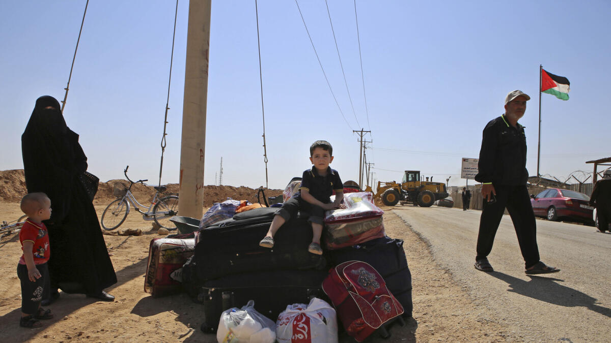 A Syrian refugee boy sits on top of his family's belonging while waiting to leave Zaatari refugee camp, in Mafraq, Jordan.