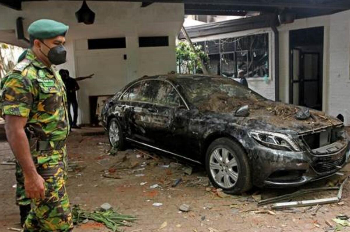 A member of security personnel stands guard next to a damaged car inside the residence of Sri Lanka's Prime Minister, a day after it was vandalised by the protestors in Colombo on July 10, 2022. (Photo: AFP)