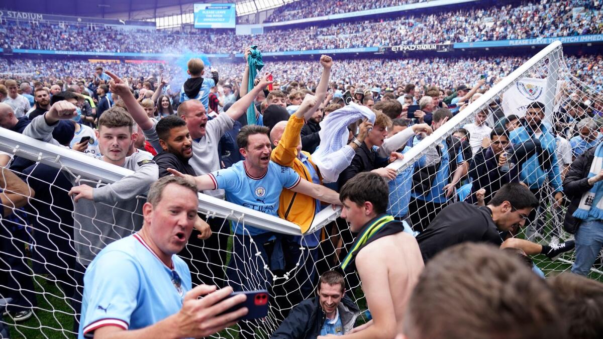 Manchester City fans celebrate on the pitch. — AP