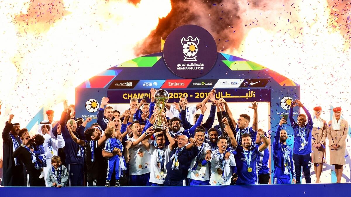 Team members of Al Nasr lift the Arabian Gulf Cup trophy as they celebrate winning.