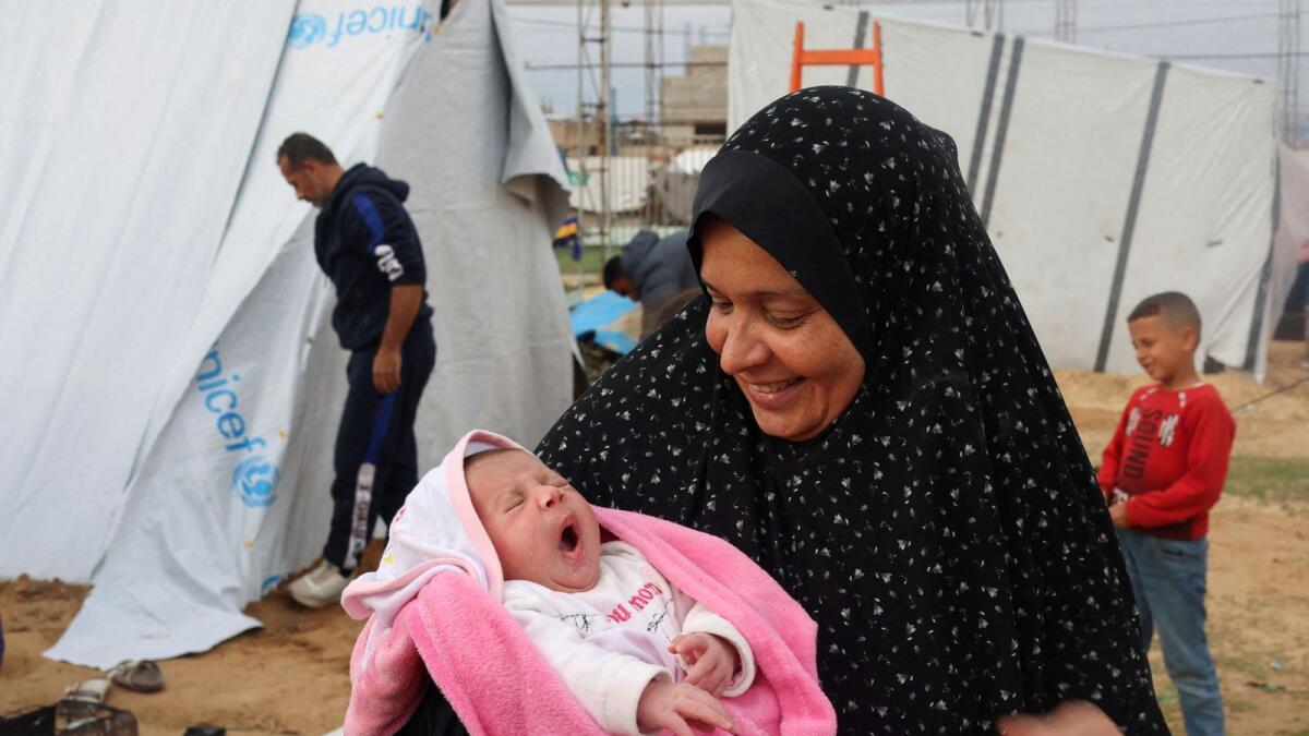 Mervat Salha, the grandmother of Palestinian baby girl Mariam, holds her outside a tent where they shelter with their displaced family who fled their house due to Israeli strikes, in Rafah. - Reuters