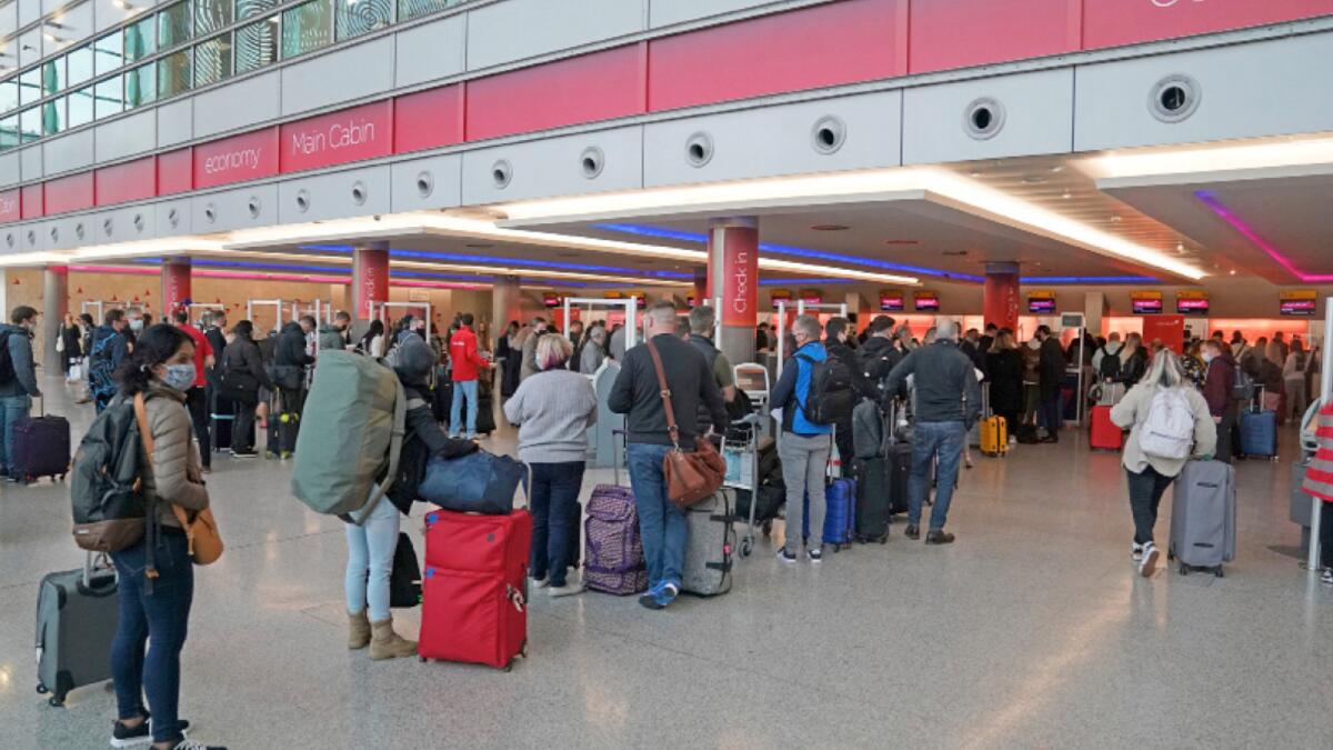 Passengers queue at London's Heathrow Airport's. – AP