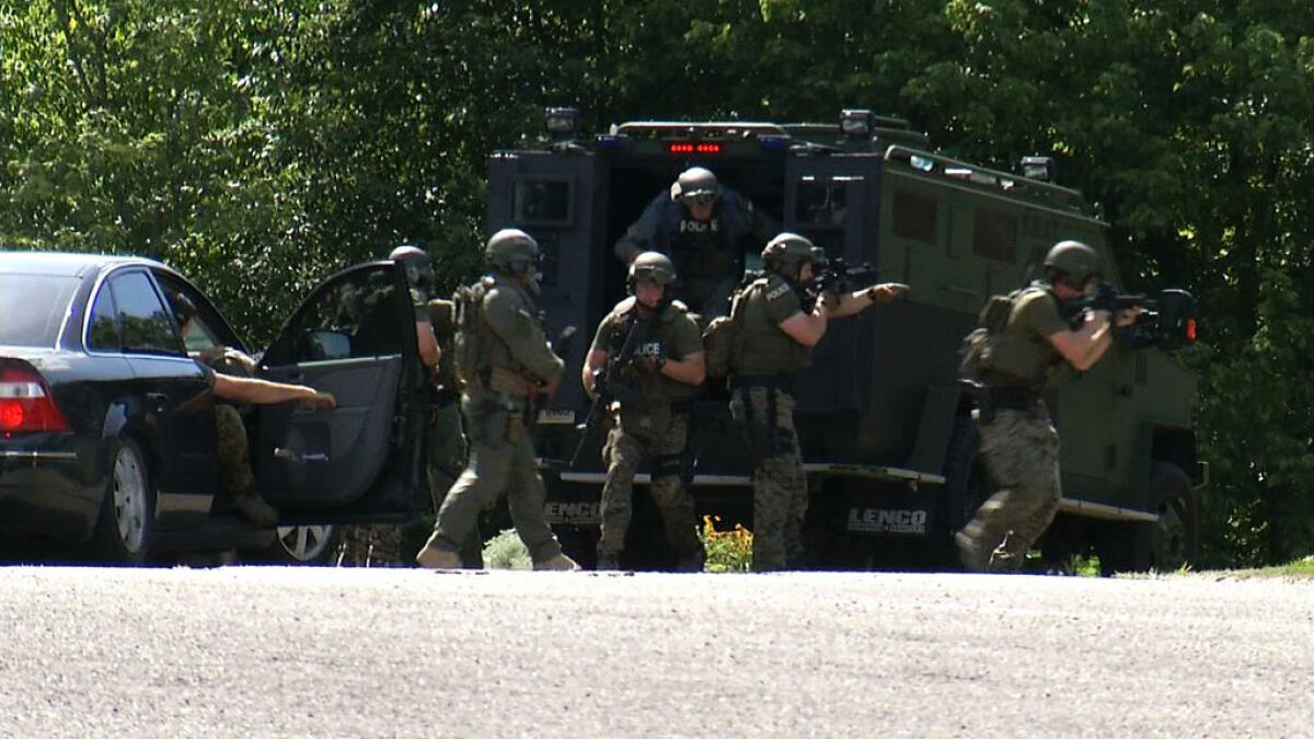 In this frame from video, law enforcement officers surround a house in Hixson, Tenn., Thursday, July 16, 2015. A gunman unleashed a barrage of fire at two sites a few miles apart in Chattanooga, killing several, officials said. The attacker was also killed. (AP Photo/Alex Sanz)