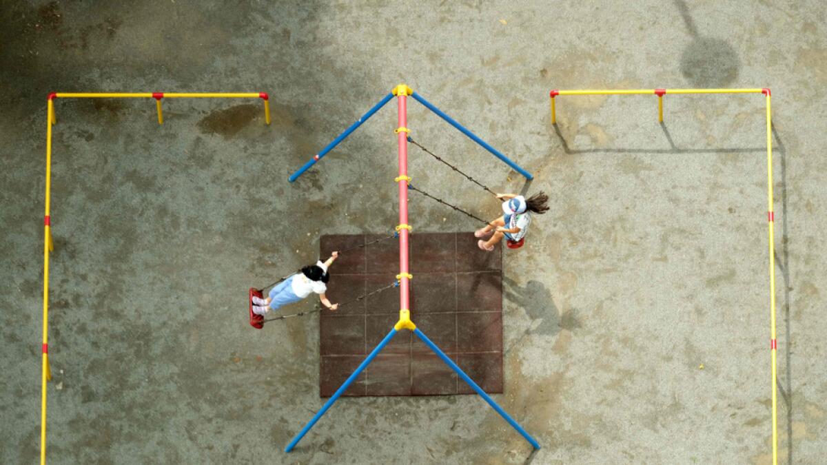 This overhead image shows children playing on swings at a park in Tokyo on July 26, 2020. Photo: AFP