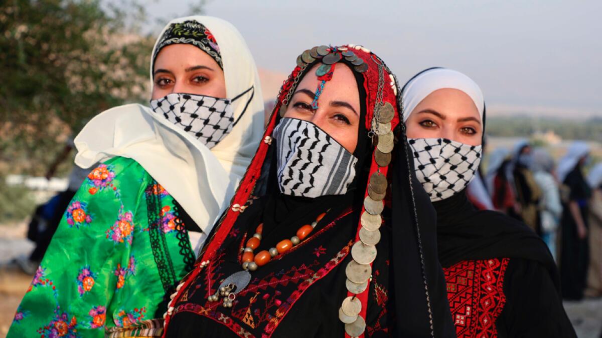 Palestinian women wearing protective masks amid the Covid-19 pandemic pose in their traditional attire during an event to celebrate the Palestinian Traditional Dress Day. Photo: AFP