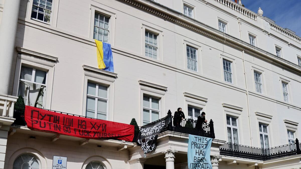 A group of squatters display banners and a Ukrainian national flag on the facade of a mansion supposedly belonging to Russian oligarch Oleg Deripaska in Belgrave Square, central London, on March 14, 2022 as they occupy it. Photo: AFP