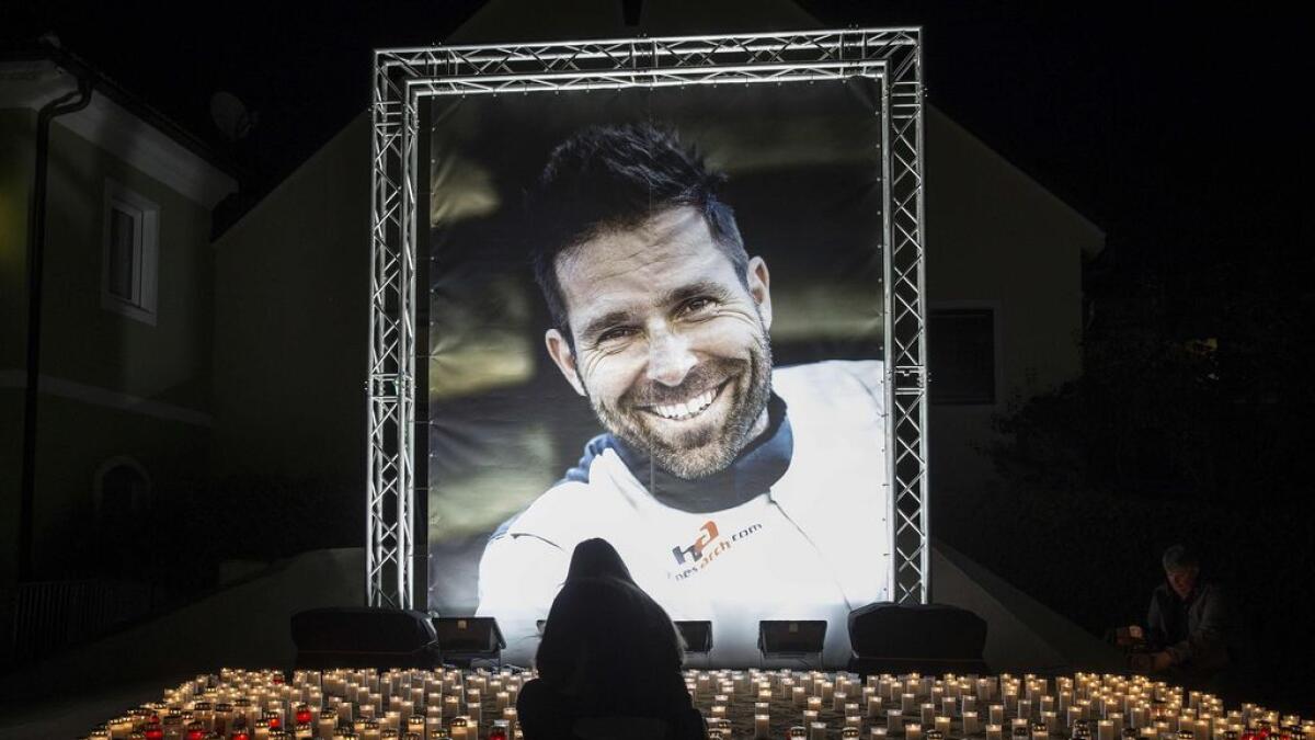 A person lights up a candle in front of a picture of Austrian racing pilot Hannes Arch during a memorial service in Trofaiach, Austria.-AFP 
