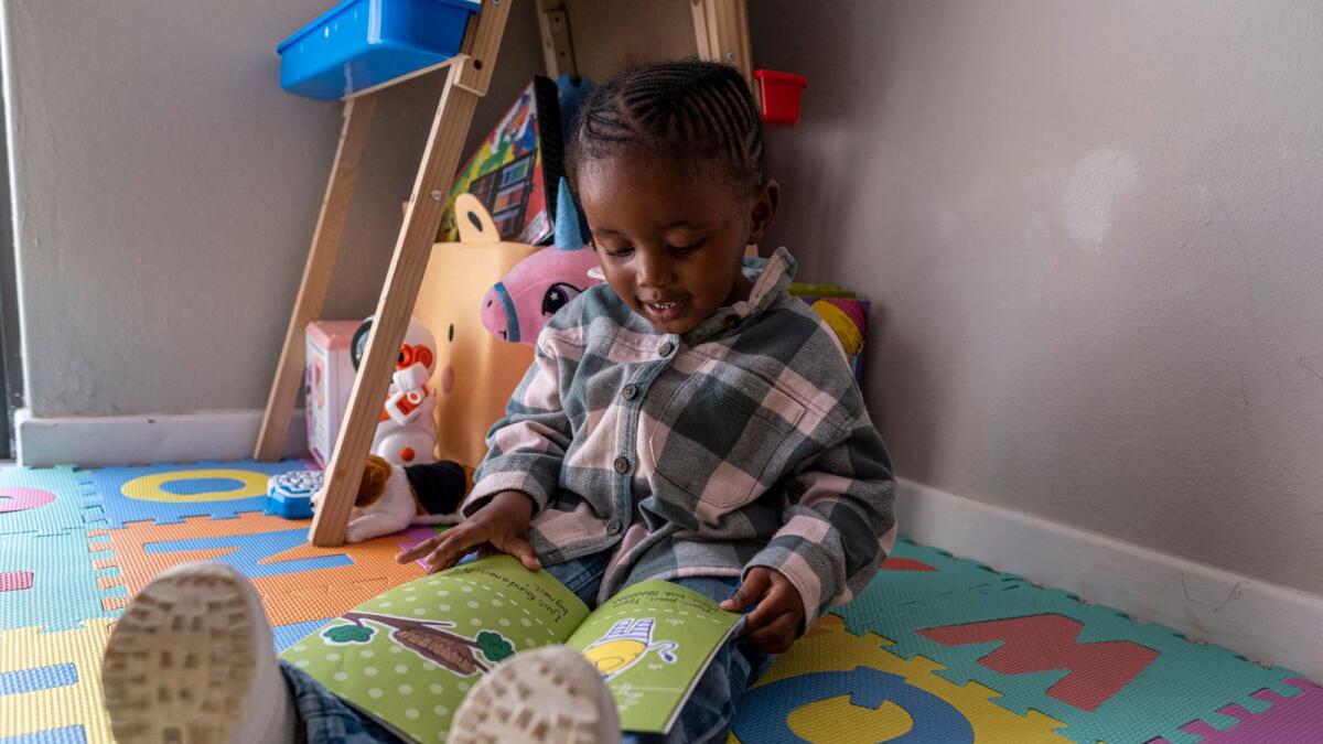 Three-year-old Lethukuthula Bhengu reads a book at her parents’ home in Johannesburg on May 13, 2023. Photo: AFP