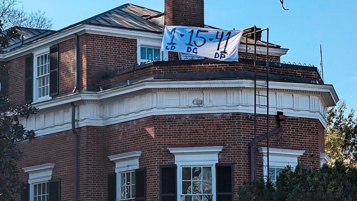 A banner with the numbers and initials of three University of Virginia football players killed in a shooting hangs from a home near the crime scene. — AP