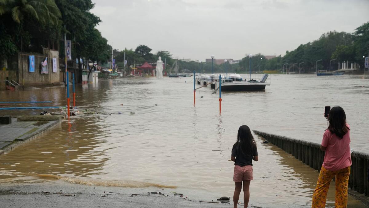 Girls look at a flooded riverside park due to enhanced rains brought about by Typhoon Doksuri in Marikina city, Philippines, on Thursday.  — AP