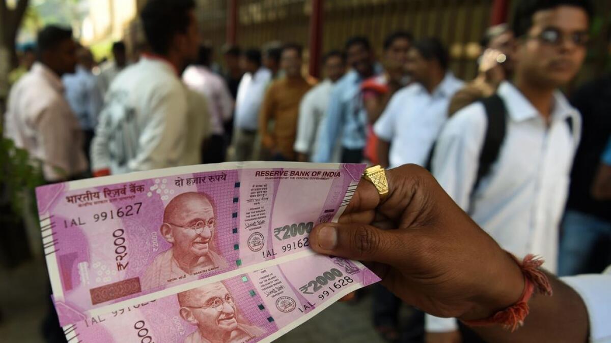 An Indian man displays new 2000 rupee notes