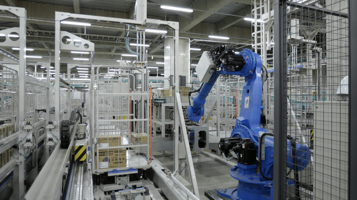 An industrial robot manufactured by Yaskawa Electric Corp. loads cases of pharmaceutical products onto a cargo cart