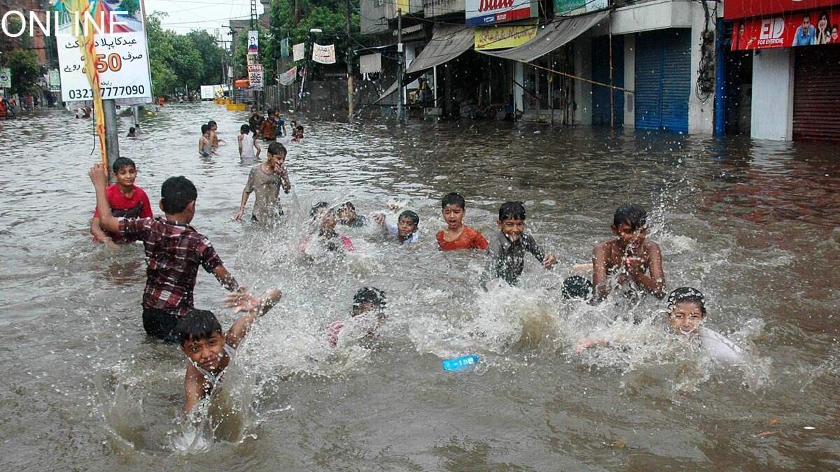Children play in rainwater in Lahore as downpour flooded the streets on Tuesday.