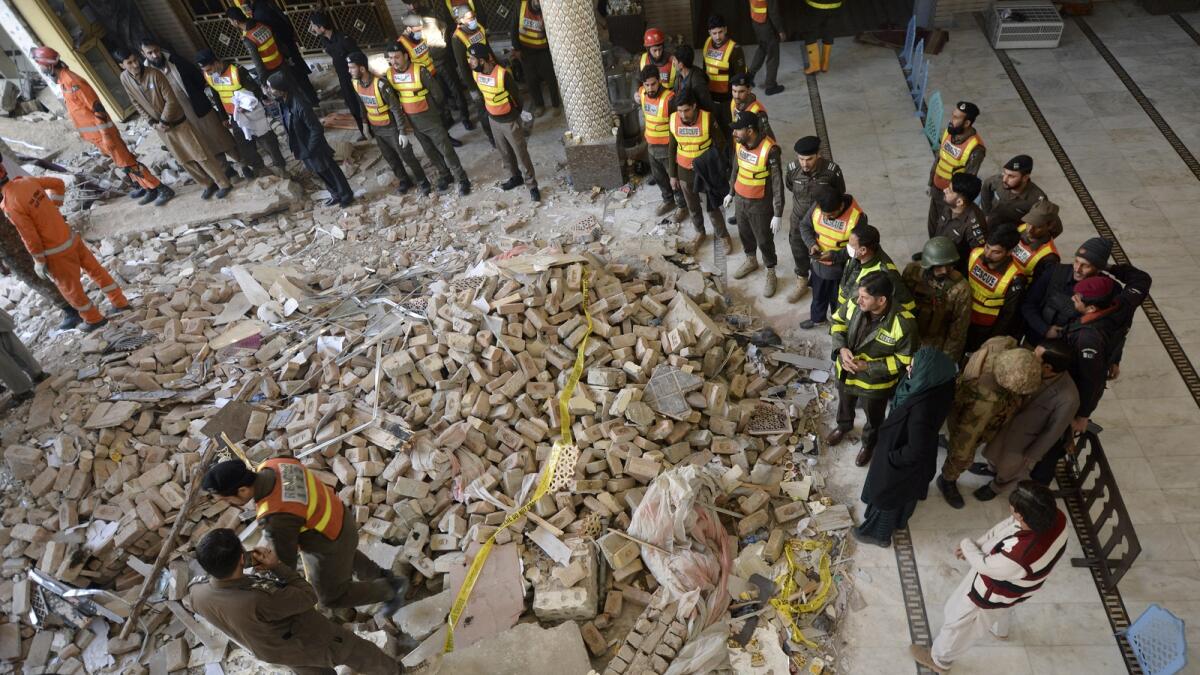 Rescue workers gather as they conduct an operation to clear the rubble and find the bodies at the site of a suicide bombing in Peshawar. — AP