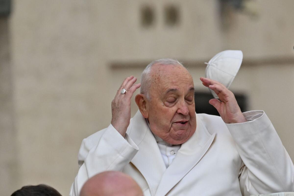 Wind blows Pope Francis' cap off his head as he arrives for his general audience in St. Peter Square at the Vatican on March 13, 2024.   — AFP