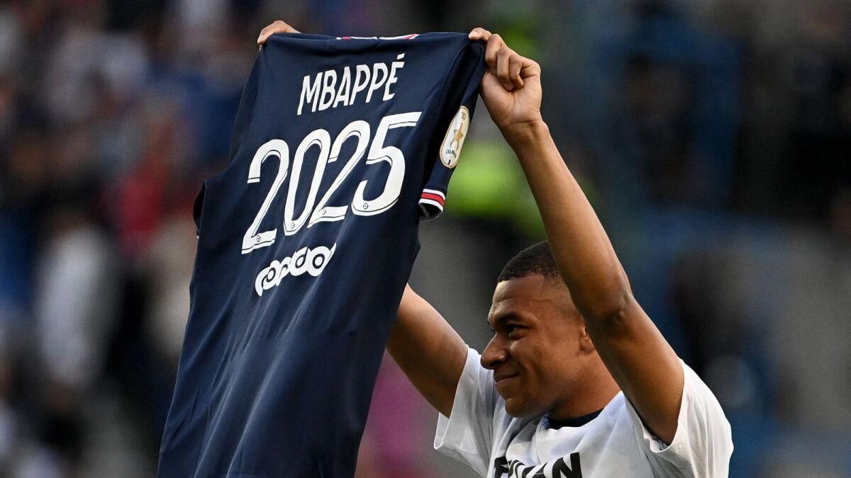 Paris Saint-Germain's  Kylian Mbappe poses with a jersey after the announcement that he will be staying at PSG until 2025. — AFP