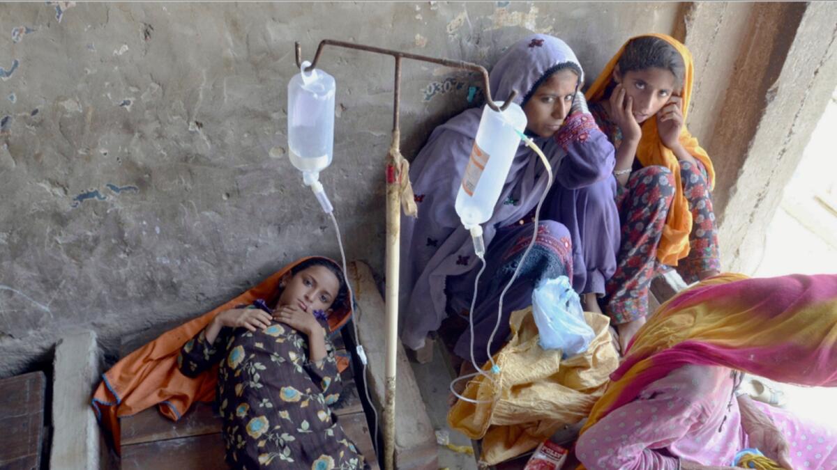 A sick girl and women receive treatment at a temporary medical centre setup in an abandoned building in Jaffarabad, a flood-hit district of Baluchistan province. — AP