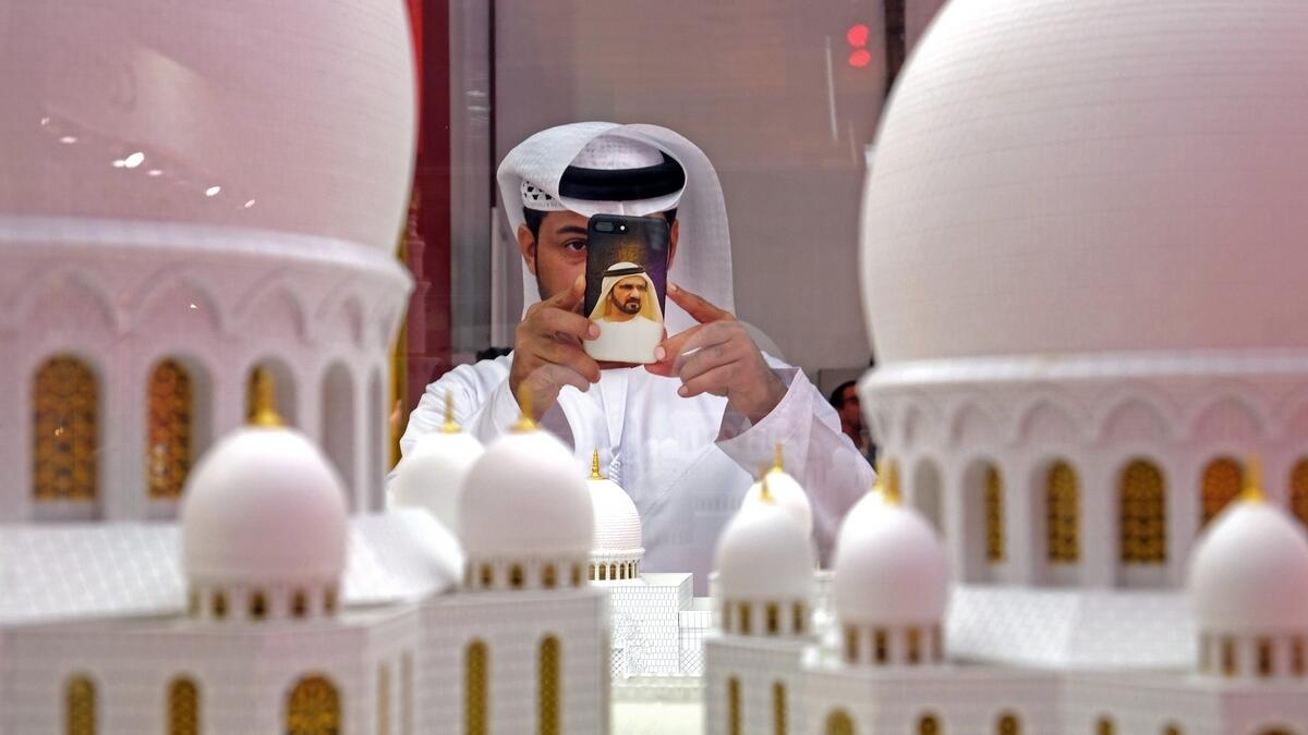 A visitor takes a photo of the Sheikh Zayed Grand Mosque at the Abu Dhabi pavilion during the Arabian Travel Market in Dubai.