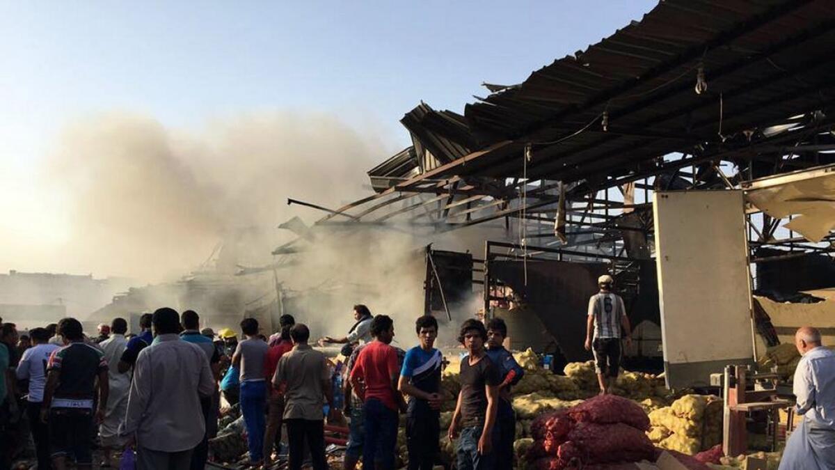 Smoke rises  while civilians gather at the scene of bomb attack in Jameela market in the Iraqi capitals crowded Sadr City neighborhood Baghdad.  