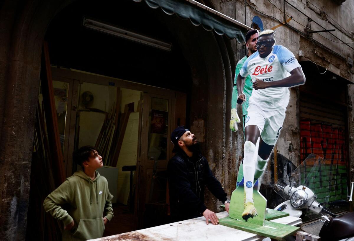 A fan looks at cardboards cutouts of Napoli's players Victor Osimhen and Alex Meret in the Spanish quarters. — Reuters