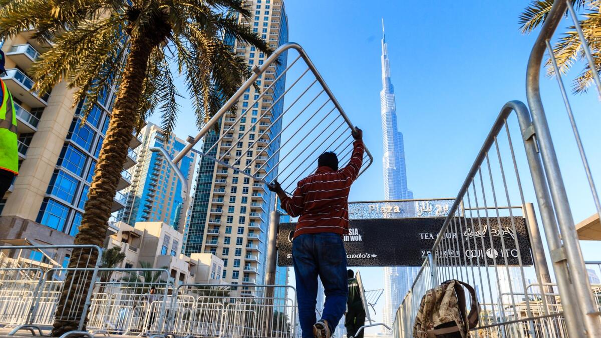 Signboards set up for the visitors at Downtown Dubai and (below) workers setting up  barricades to organise the crowd at Burj Plaza.
