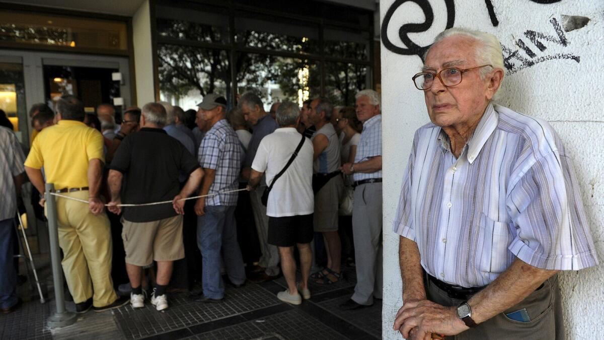 A pensioner (R) stands outside a National Bank branch as others line up to receive part of their pensions in the city of Thessaloniki, Greece July 9, 2015. A race to save Greece from bankruptcy and keep it in the euro gathered pace on Wednesday when Athens formally applied for a three-year loan and European authorities launched an accelerated review of the request. REUTERS/Alexandros Avramidis