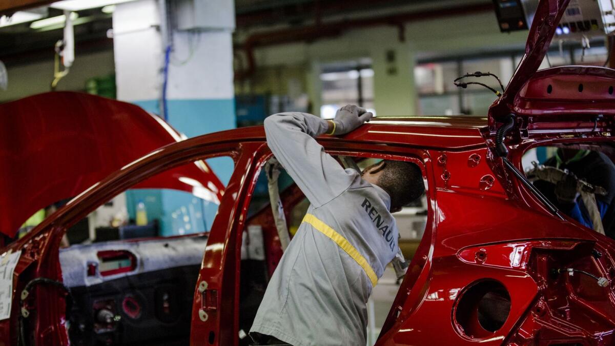 An employee carries out final inspections on the body shell of a freshly painted Nissan Micra automobile inside the Renault SA factory in Flins, France. — File photo