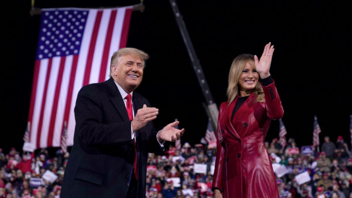 President Donald Trump and first lady Melania Trump wave to the crowd as they walk off stage after a campaign rally for Senate Republican candidates. — AP