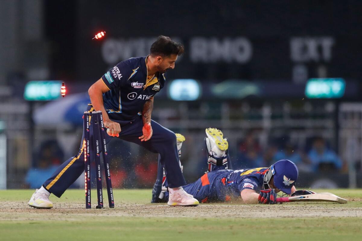 Mohit Sharma (left) of Gujarat Titans looks on after removing the bails as Ayush Badoni of Lucknow Super Giants fails to make his ground. — IPL