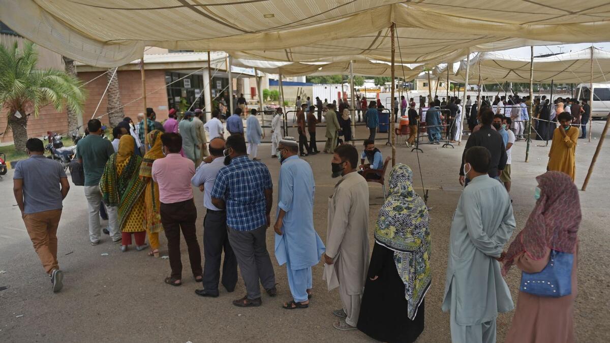 People wait for their turn to receive a dose of the Covid-19 vaccine at a camp organised in Karachi. Photo: AFP