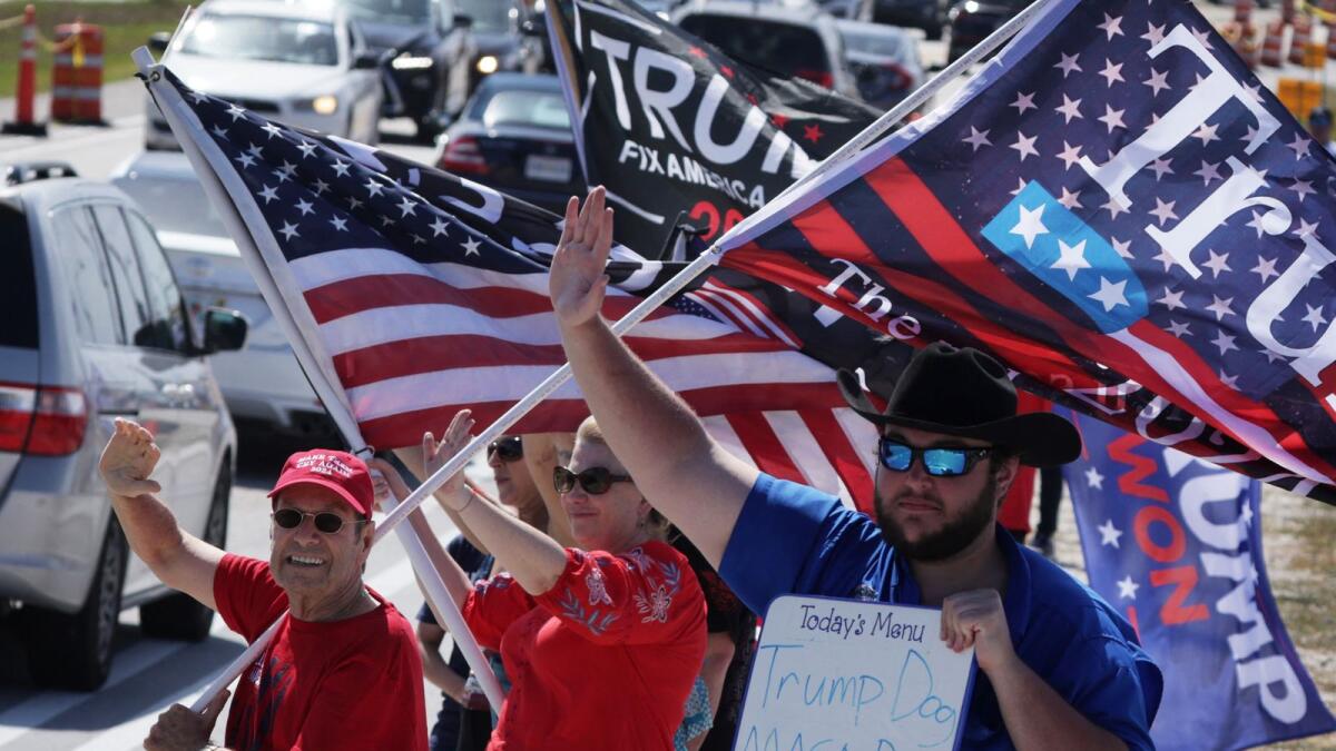 Supporters hold flags and wave to traffic as they gather to show near former U.S. President Donald Trump's Mar-a-Lago home on Saturday in Palm Beach, Florida. -- AFP