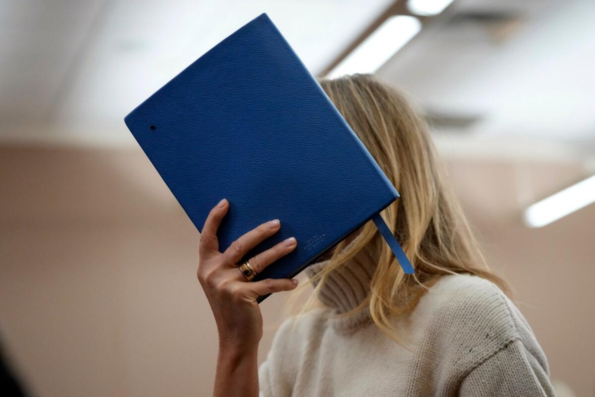 Actor Gwyneth Paltrow shields her face with a blue notebook as she exits a courtroom on March 21