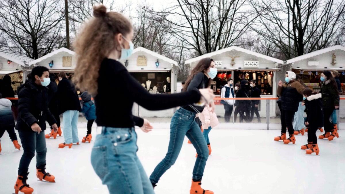 People wear face masks to curb the spread of Covid-19 as they ice skate at a funfair in Paris. — AP