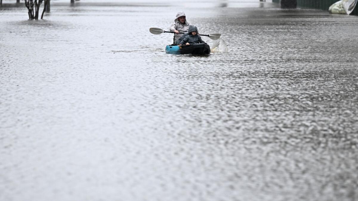 People kayak along a flooded street from the overflowing Hawkesbury river due to torrential rain in the Windsor suburb of Sydney on July 4, 2022. Photo: AFP