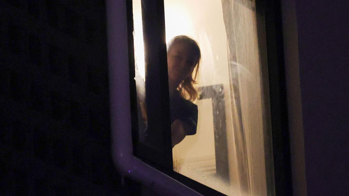 A woman believed to be Czech Republic's Renata Voracova looks out the window at a government detention centre where Serbia's tennis champion Novak Djokovic is reported to be staying in Melbourne. — AFP