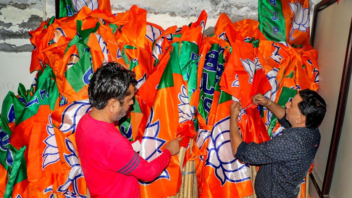 Workers arrange BJP flags ahead of Lok Sabha elections in Jammu. — PTI