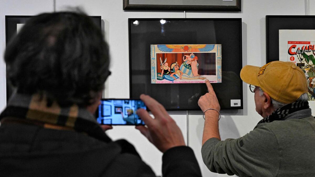 People look at a drawing by late French cartoonist Albert Uderzo, the original cover of 'Asterix and Cleopatra', on display at Millon auction house in Brussels. — AFP