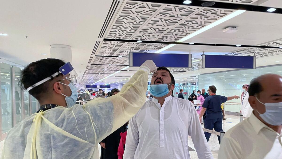 Saudi medical staff give oral medication to the first batch of Muslims from international flights on their way to Umrah on November 1, 2020.