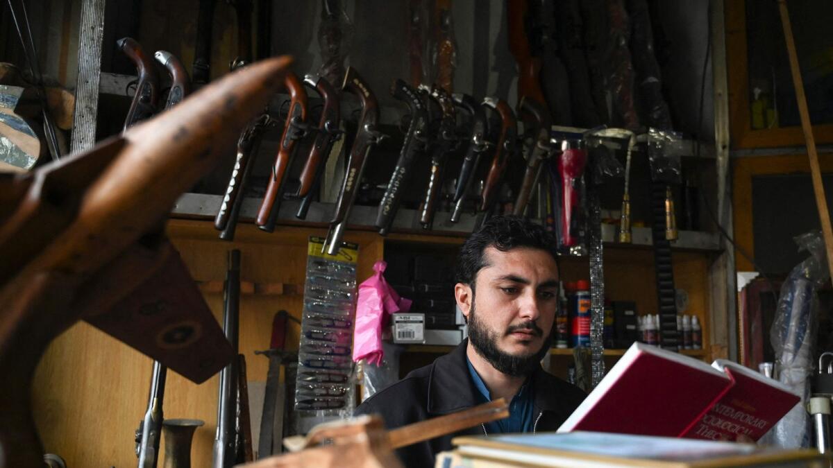 An arms dealer Muhammad Jahanzeb reads a book at his shop in Darra Adamkhel town, some 35 kilometres south of Peshawar. — AFP