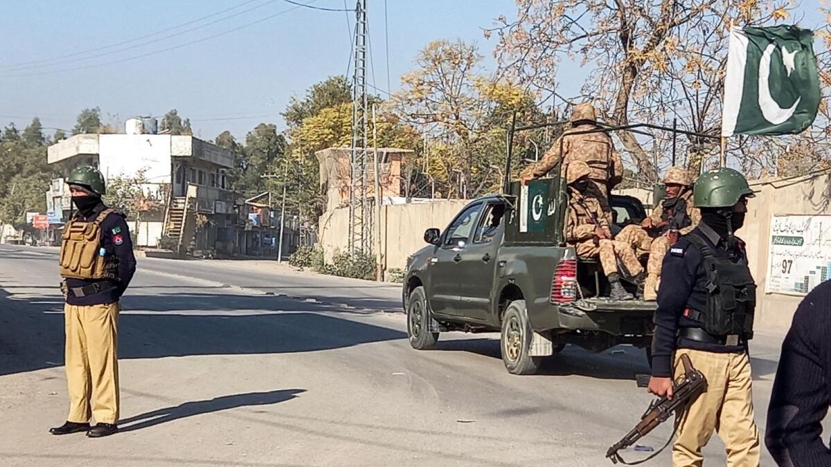 An Army vehicle patrols, past police officers stand guard along a road, near cantonment area in Bannu, Pakistan. — Reuters file
