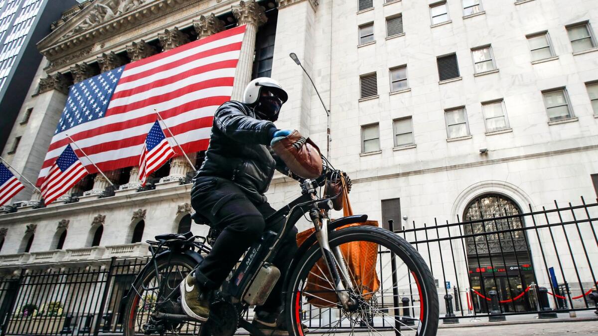 A delivery worker rides his electric bicycle past the New York Stock Exchange on March 16, 2020. — AP file