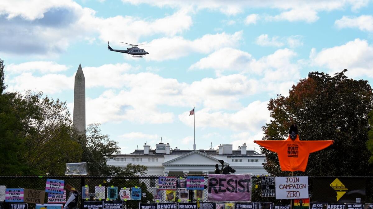 Helicopter passes over the White House, seen behind a fence and protest posters, the day before the U.S. presidential election in Washington, D.C., U.S., November 2, 2020.