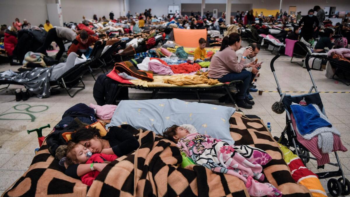 A mother sleeps with her children among many others in a temporary shelter hosting the Ukrainian refugees located in a former shopping center near the city of Przemysl, on March 08, 2022. Photo: AFP