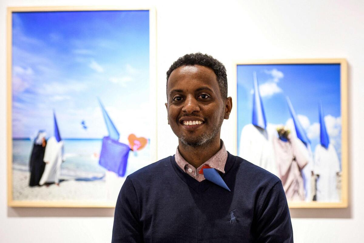 Sudanese photographer Hashim Nasr poses in front of one of his pictures during an exhibition concert at the Goethe institute in the Egyptian capital Cairo on November 26, 2023. — AFP
