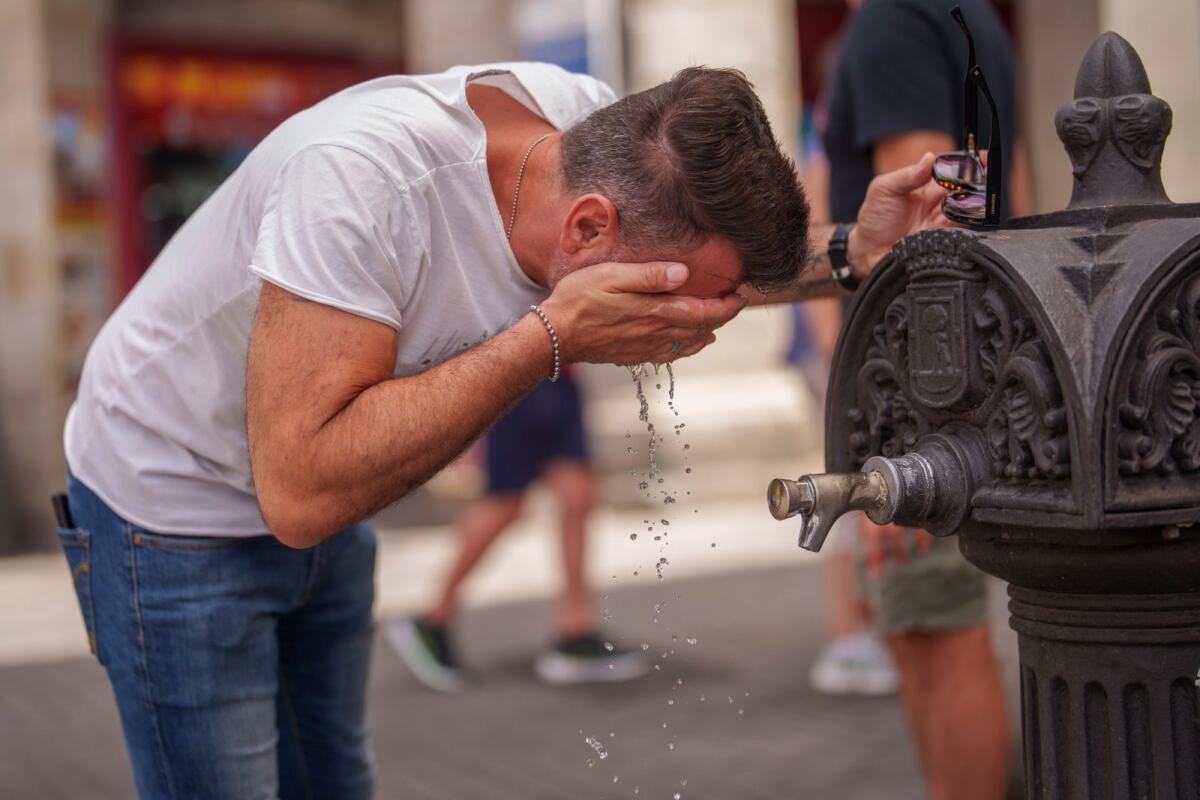 A man cool off at a fountain during a hot and sunny day of summer in Madrid, Spain, Photo: AP file