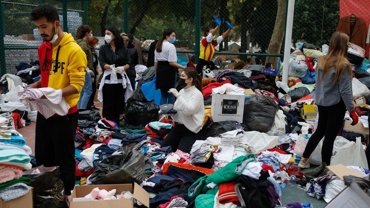 People who became homeless due to the earthquake go through handout clothes at a basketball court where tents for the homeless families had been set up, Izmir, Turkey.
