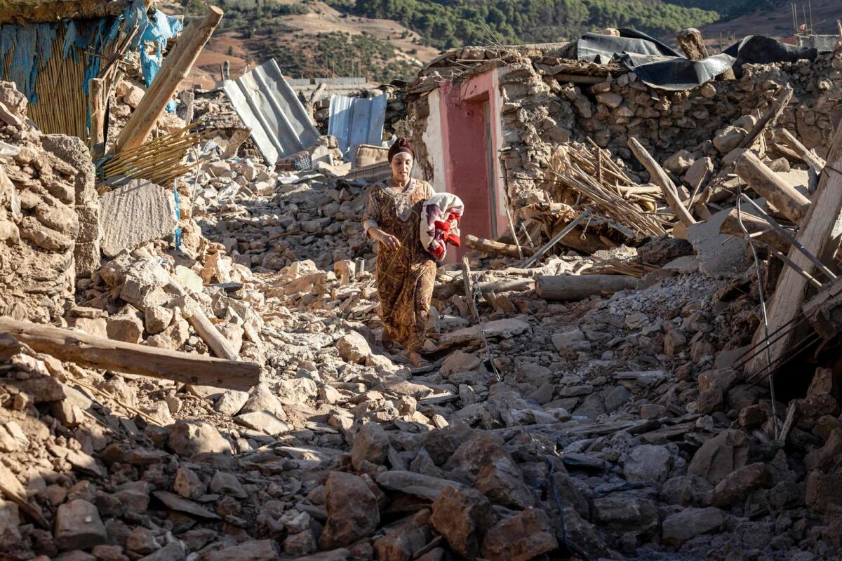 A woman walks past destroyed houses after an earthquake in the mountain village of Tafeghaghte, southwest of the city of Marrakesh, on September 9, 2023. — AFP