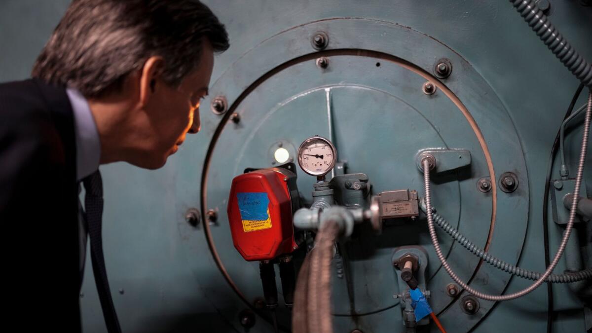 Josh London, senior vice president at Glenwood Management Corp., peers into the port hole of a natural gas fired boiler, located in the basement of The Grand Tier luxury apartment building, that his company uses to produce liquid carbon dioxide, Tuesday, April 18, 2023, in New York. — AP