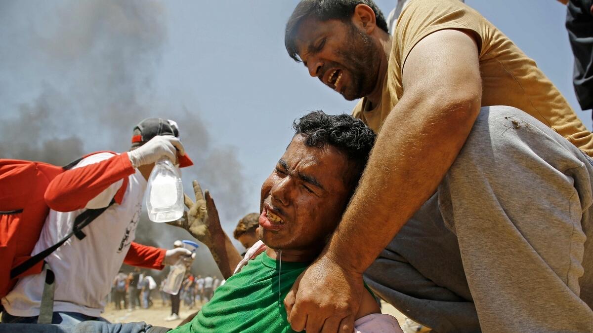 A Palestinian man assists a wounded protestor during clashes.- AFP