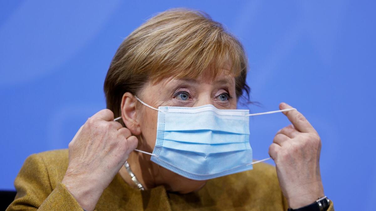 German Chancellor Angela Merkel takes off her face mask as she arrives for a news conference on extending coronavirus restrictions at the Chancellery in Berlin, Germany November 25, 2020.